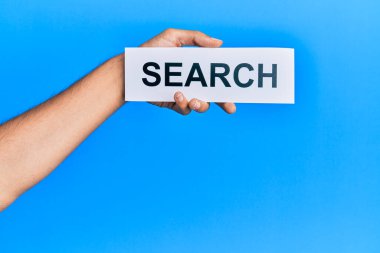 Hand of caucasian man holding paper with search word over isolated blue background