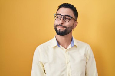 İspanyol genç adam iş kıyafetleri ve gözlük takıyor gülümsüyor yan bakıyor ve düşünüyor.. 