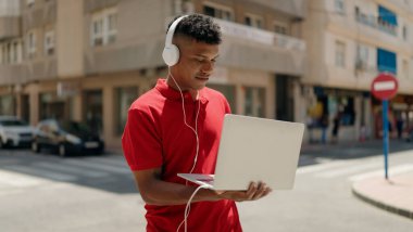 Young latin man smiling confident listening to music at street