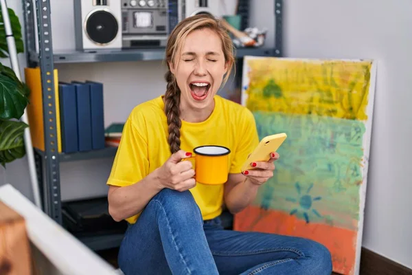 Junge Blonde Künstlerin Trinkt Kaffee Mit Smartphone Kunstatelier — Stockfoto