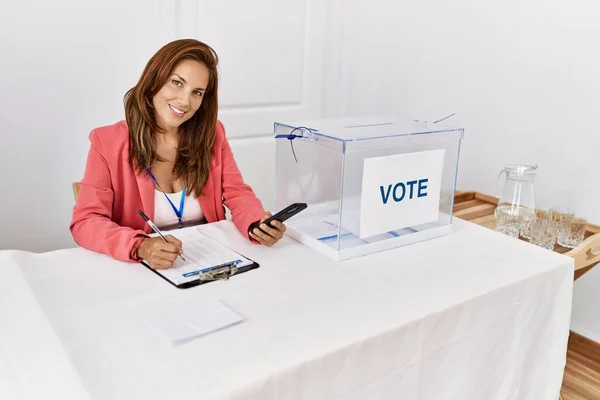 Young Latin Woman Writing Checklist Using Smartphone Working Electoral College — Stock Photo, Image