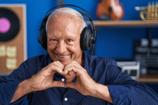 Starszy Siwowłosy Mężczyzna Artysta Słuchając Muzyki Robi Gest Serca Rąk — Zdjęcie stockowe