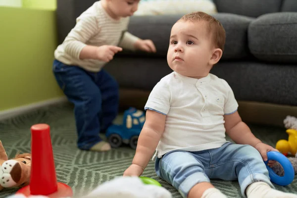 Dwa Urocze Maluchy Bawiące Się Zabawkami Siedzącymi Podłodze Domu — Zdjęcie stockowe