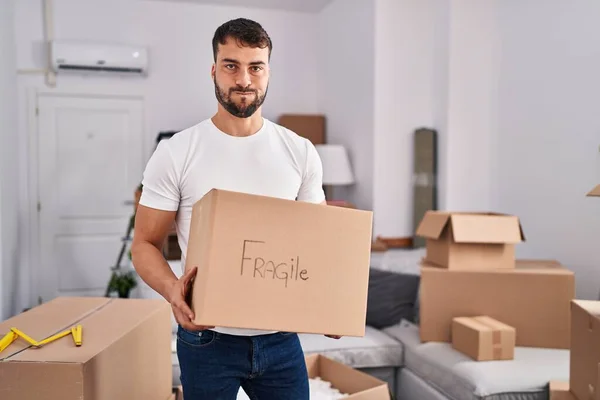 Handsome Hispanic Man Moving New Home Holding Fragile Box Puffing — Stockfoto