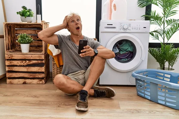 Genç Sarışın Adam Çamaşır Yıkıyor Akıllı Telefon Kullanıyor Deli Elleri — Stok fotoğraf