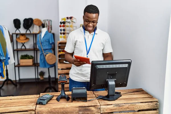 Young african man working as shop assistance using touchpad at retail shop