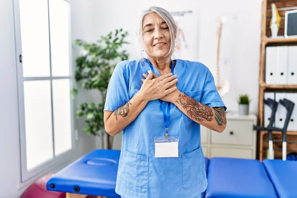 Medelålders Gråhårig Kvinna Klädd Sjukgymnast Uniform Läkarmottagningen Leende Med Händerna — Stockfoto