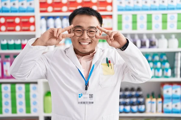 Chiński Młody Człowiek Pracujący Aptece Robi Symbol Pokoju Palcami Twarzy — Zdjęcie stockowe