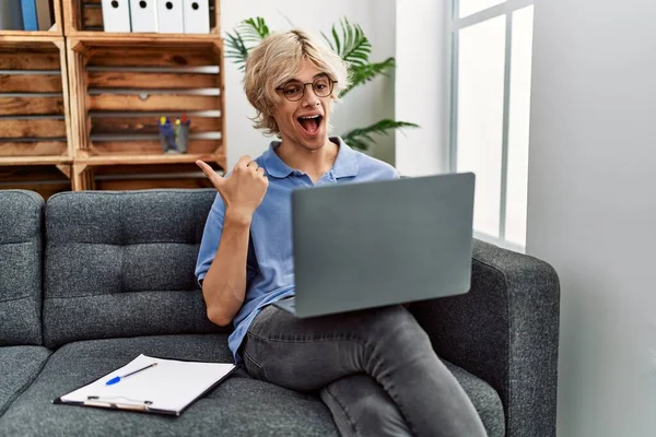 Young Man Working Using Computer Laptop Sitting Sofa Pointing Thumb — Stockfoto
