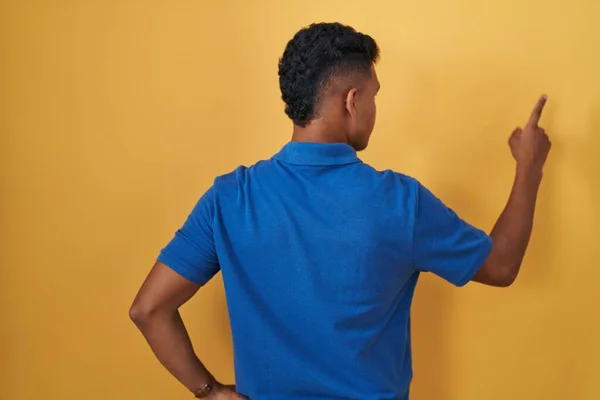 Young Hispanic Man Standing Yellow Background Posing Backwards Pointing Ahead — Stock Photo, Image