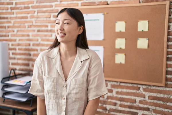 Chinese young woman working at the office doing presentation looking away to side with smile on face, natural expression. laughing confident.