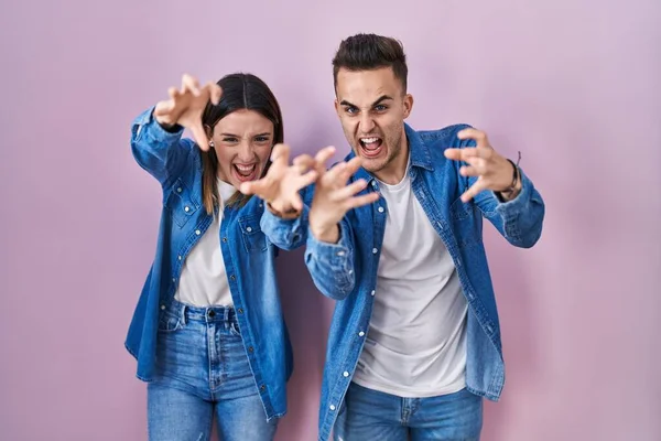 Young Hispanic Couple Standing Pink Background Shouting Frustrated Rage Hands — Stockfoto