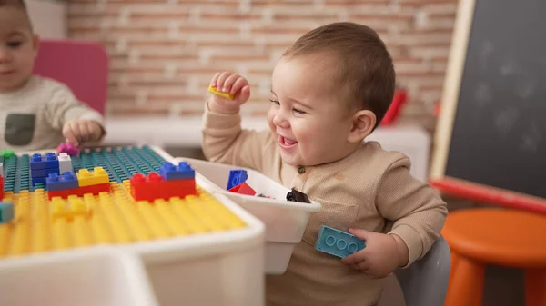 Adorable Toddler Holding Plastic Construction Blocks Sitting Table Kindergarten — Stok fotoğraf