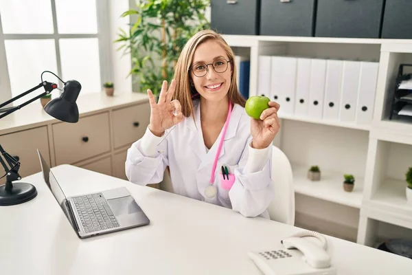 Young Blonde Doctor Woman Holding Green Apple Clinic Doing Sign — Stok fotoğraf