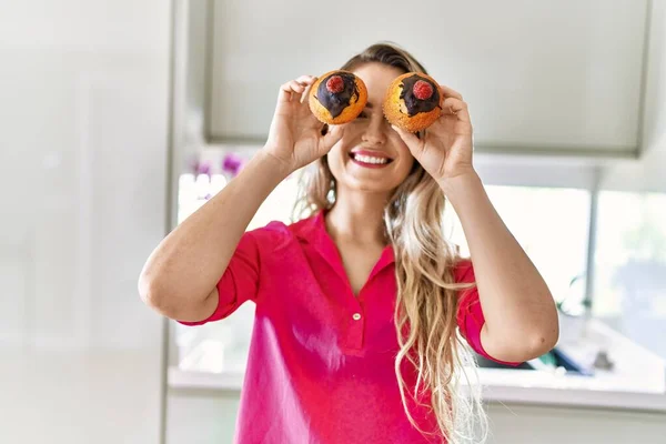 Young Woman Smiling Confident Holding Cupcakes Eyes Kitchen — Stock fotografie