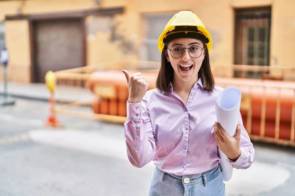 Hispanic Girl Wearing Architect Hardhat Construction Site Pointing Thumb Side — Stockfoto