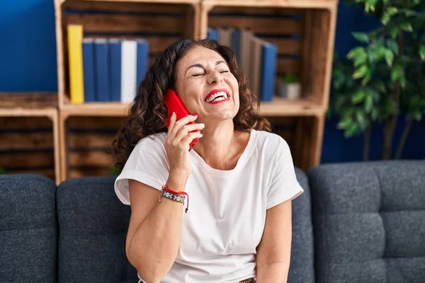 Middle age hispanic woman speaking on the phone at home