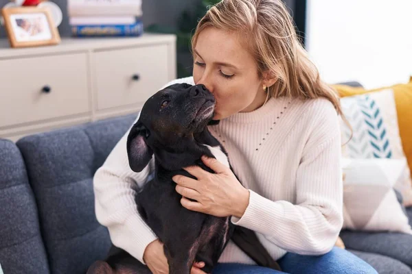 Young Blonde Woman Hugging Kissing Dog Sitting Sofa Home — Stock Photo, Image