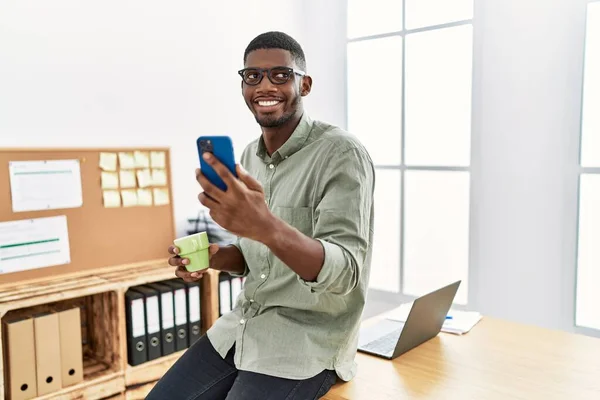 Νεαρός Αφροαμερικάνος Που Χρησιμοποιεί Smartphone Πίνοντας Καφέ Στο Γραφείο — Φωτογραφία Αρχείου