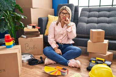 Young hispanic woman moving to a new home sitting on the floor thinking worried about a question, concerned and nervous with hand on chin 