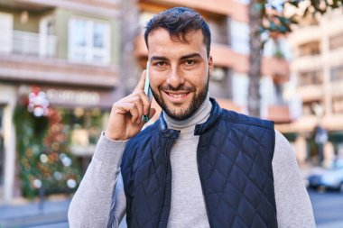 Genç İspanyol adam gülümsüyor. Kendine güveniyor. Sokakta akıllı telefondan konuşuyor.