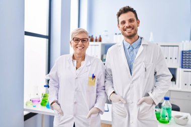 Mother and son scientist partners standing at laboratory