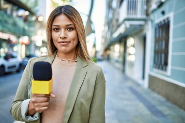 Sokakta mikrofon kullanan kendine güvenen genç Latin kadın.