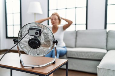 Evde yelpaze kullanan genç sarışın kadın.