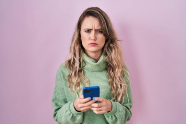 Kafkasyalı genç bir kadın akıllı telefon kullanıyor şüpheci ve gergin mesajlar yazıyor, sorun yüzünden surat asıyor. negatif kişi. 