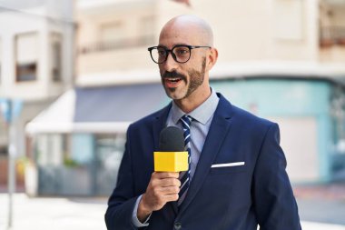 Sokakta mikrofon kullanan genç İspanyol muhabir.