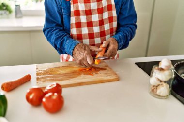 Kıdemli adam mutfakta havuç kesiyor.