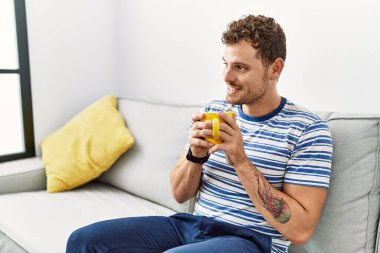 Genç İspanyol adam gülerek evde kahve içiyor.