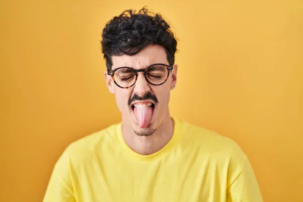 Hispanic Man Bär Glasögon Står Över Gul Bakgrund Sticker Tungan — Stockfoto