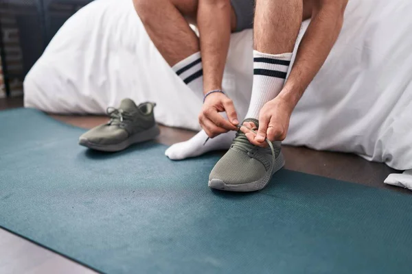 Young Hispanic Man Tying Sneaker Bedroom — Stockfoto
