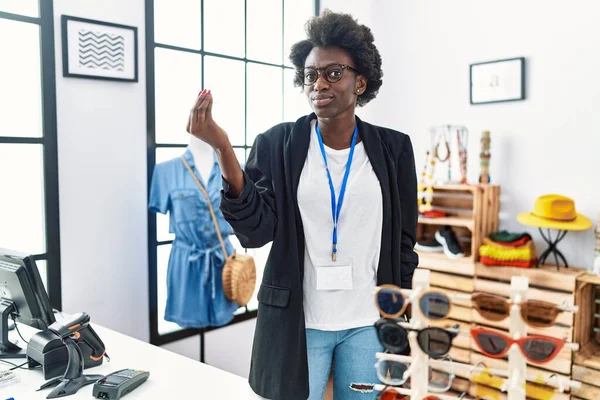 African young woman working as manager at retail boutique doing italian gesture with hand and fingers confident expression