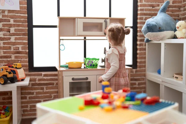 可爱的高加索女孩在幼儿园里玩着游乐厨房站在后视镜 — 图库照片
