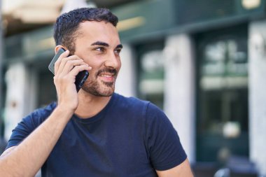 Genç İspanyol adam gülümsüyor. Kendine güveniyor. Sokakta akıllı telefondan konuşuyor.