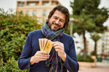 Orta yaşlı yakışıklı bir adam Norveçli kronları parkın dışında tutuyor.