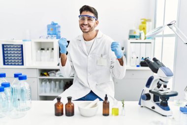 Laboratuvarda çalışan Latin asıllı genç adam gururla bağırıyor zaferi ve başarıyı kutluyor. 