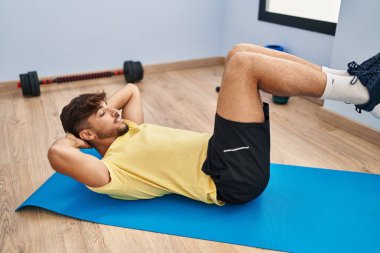 Young arab man training abs exercise at sport center