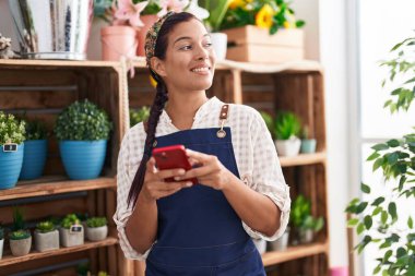 Çiçekçiye akıllı telefon kullanarak gülümseyen güzel İspanyol kadın.