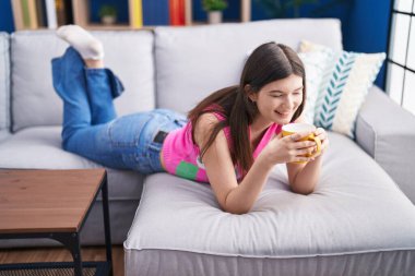 Kafkasyalı genç bir kadın evdeki kanepede kahve içiyor.