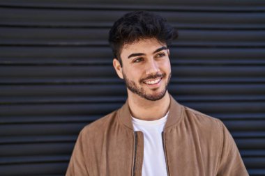 Genç İspanyol adam gülümsüyor. Siyah izole edilmiş arka planda kendine güveni olan.