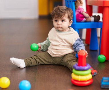 Sevimli İspanyol çocuk anaokulunda yerde oturmuş hayalarıyla oynuyor.