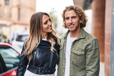 Erkek ve kadın bir arada durarak gülümsüyor.