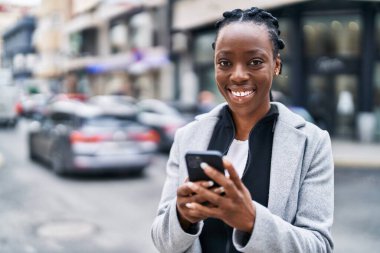 Afro-Amerikalı kadın sokakta akıllı telefon kullanarak kendine güveniyor.