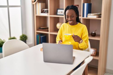 African american woman using laptop having breakfast at home