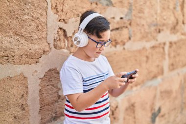 Adorable hispanic boy smiling confident playing video game at street