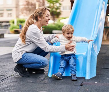 Mother and son playing on slide at park
