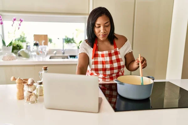 Hispanic Brunette Woman Cooking Looking Recipe Laptop Kitchen — Zdjęcie stockowe